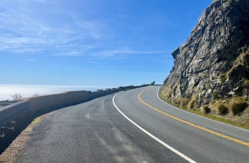 A picture of an empty road curving around a large mountain. We packed for our Big Sur adventure using our California road trip essentials list.