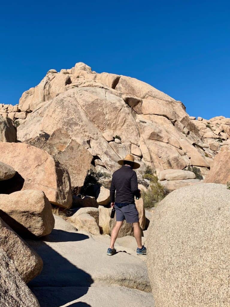 A man is walking around rocks in Joshua Tree.