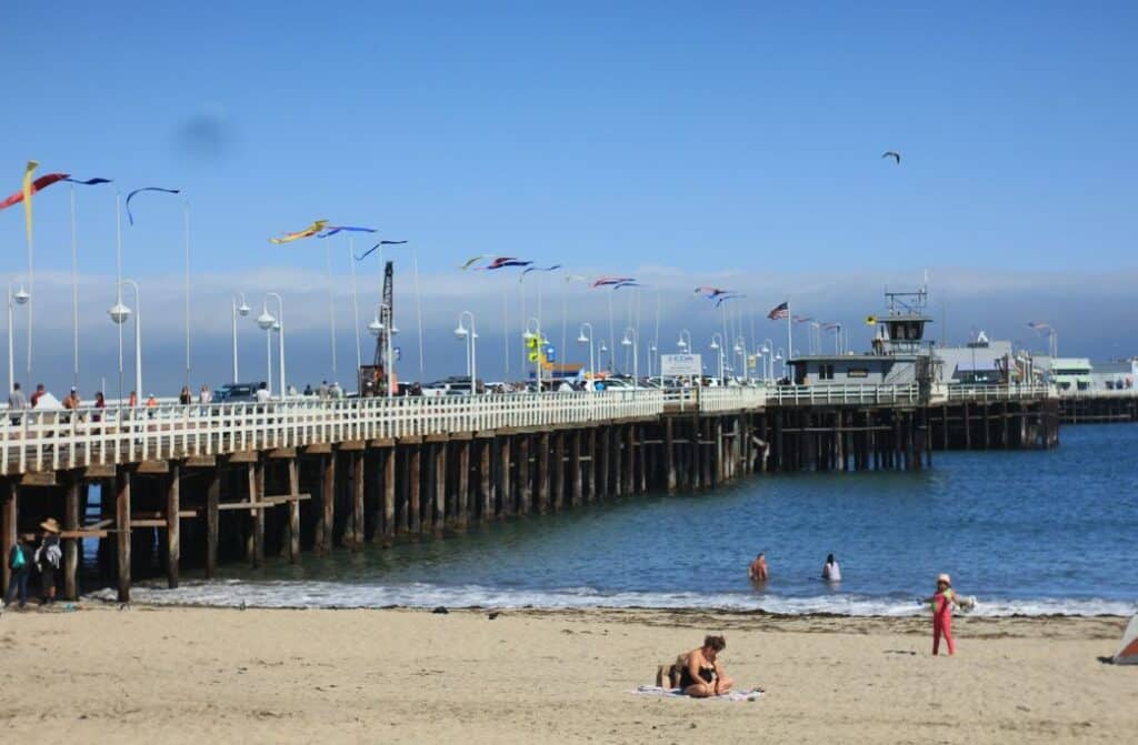 A beach and a peer with people walking on it.