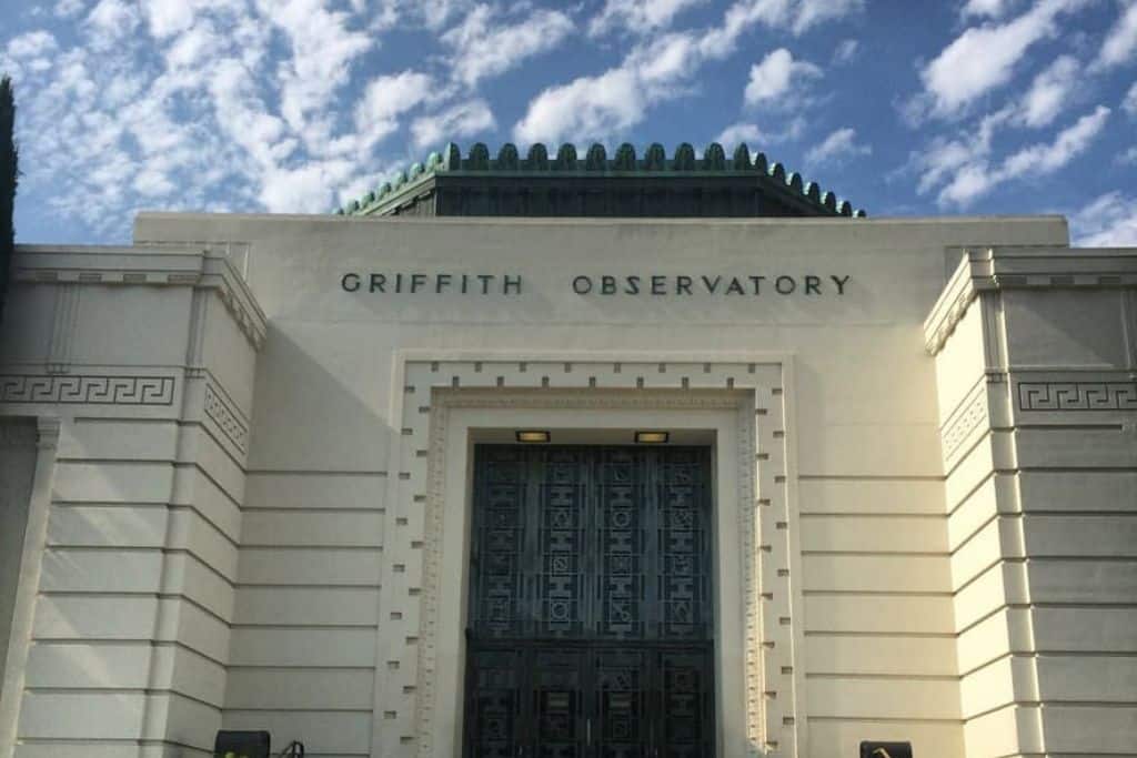 A white building that say "Griffith Observatory" on its front.