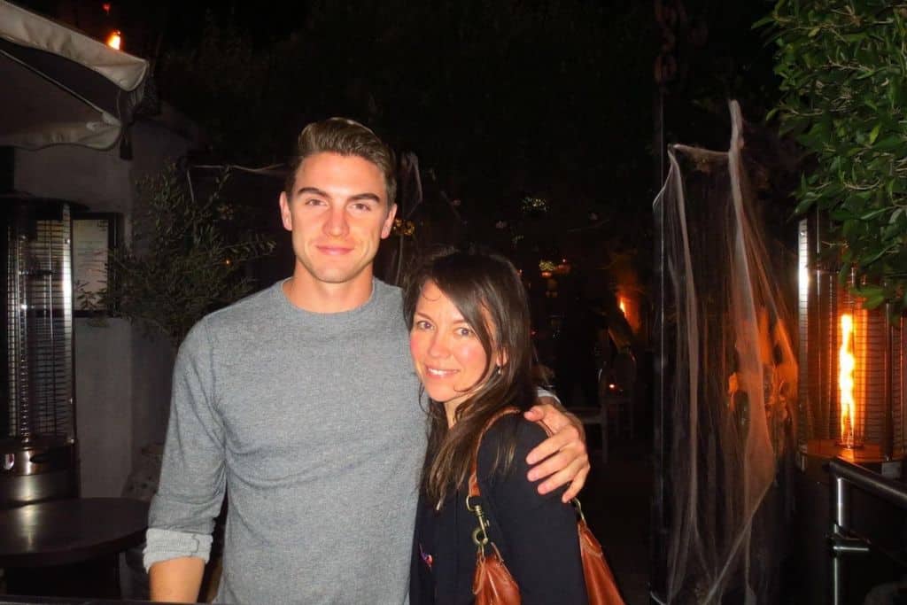 A woman and a man smile for the camera. He has his arm around her.