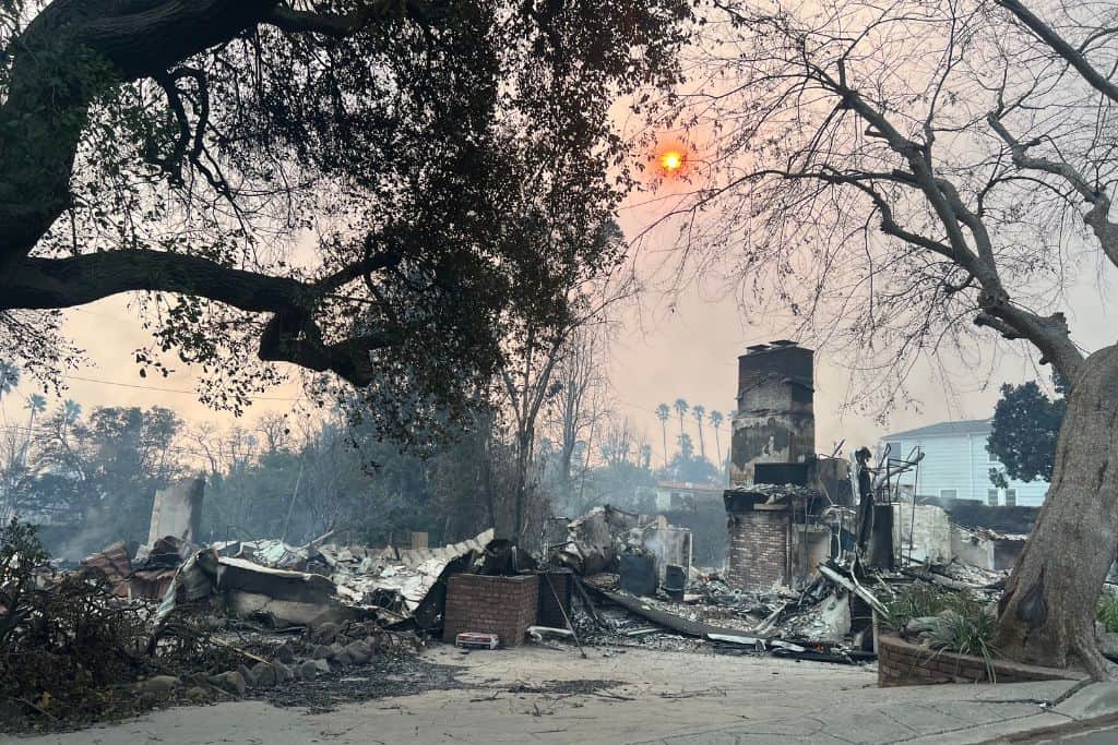 A home burnt to ashes with only the chimney standing in the remains.