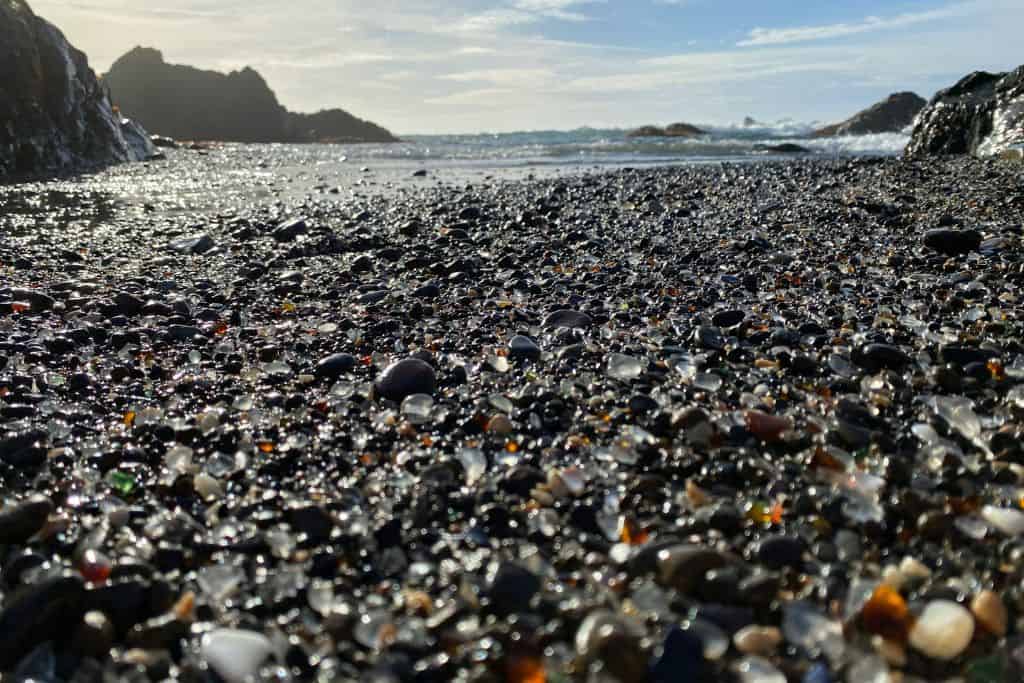 Rocks and glass rock on a beach with water in the background. Glass Beach Fort Bragg colorful sea glass