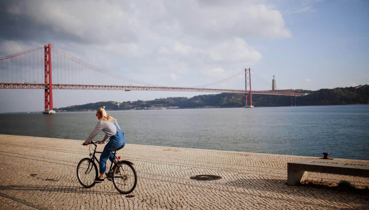 A woman on a bike on a path in front of the Golden Gate Bridge.