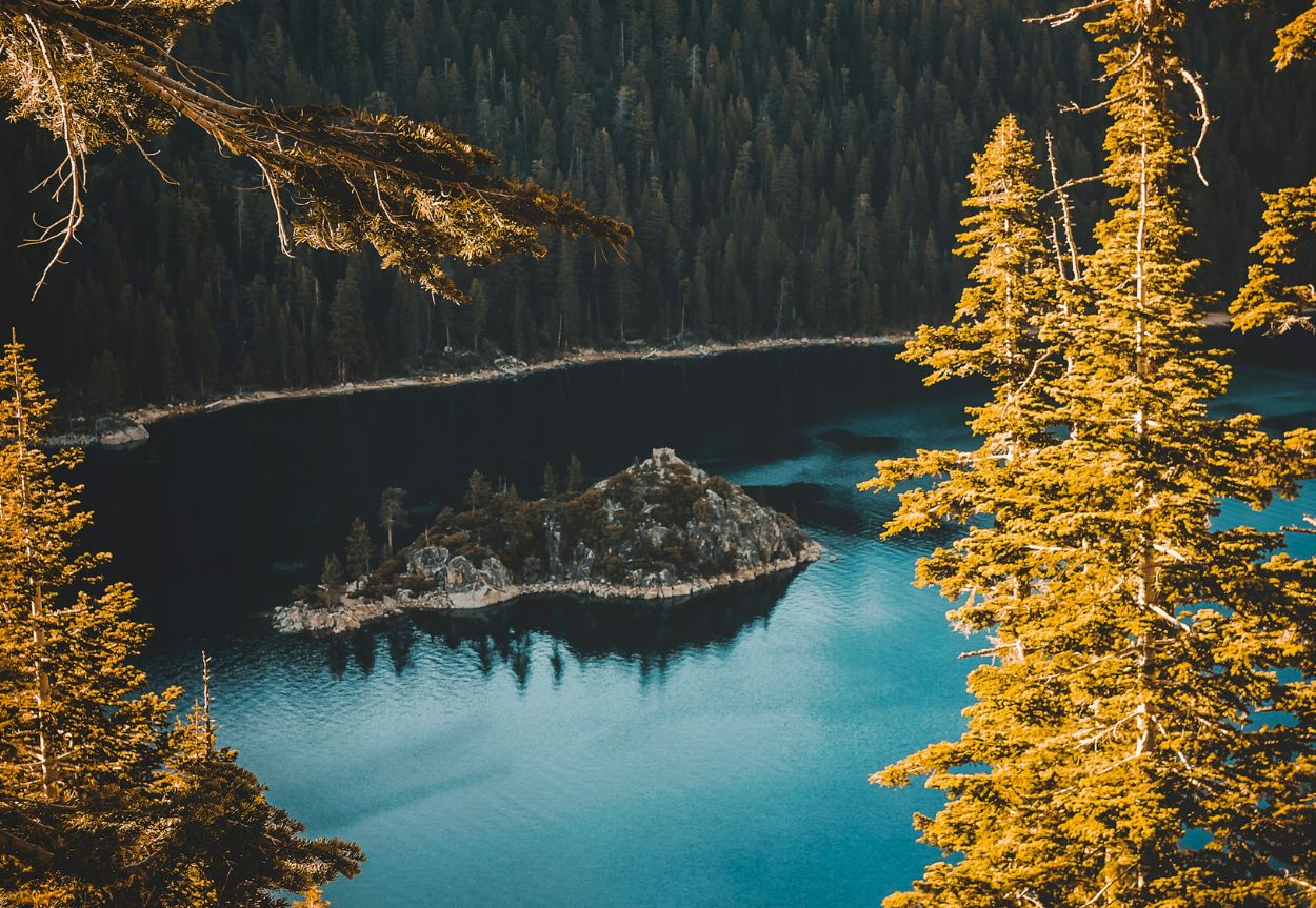 An island in the middle of a lake with fall foliage surrounding it