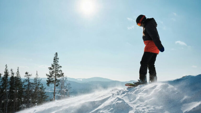 A snowboarder standing at the top of a mountain